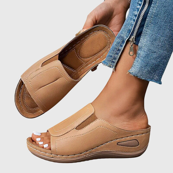 A woman walking confidently in charcoal ergonomic comfort sandals with a broad, cushioned sole.
