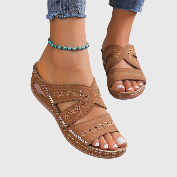 A woman walking gracefully in elegant wide-fit support sandals with an open-front design.