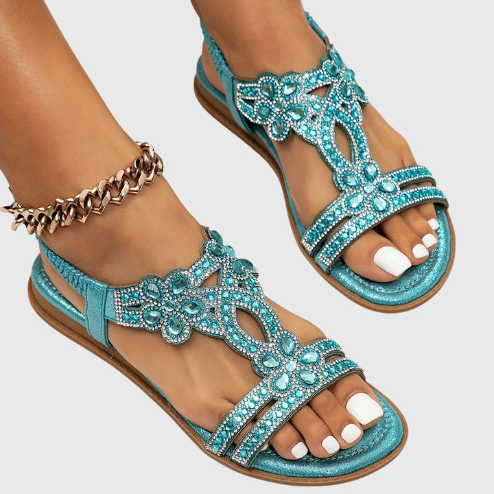 A woman wearing elegant gold open-front sandals with supportive straps and a cushioned sole.
