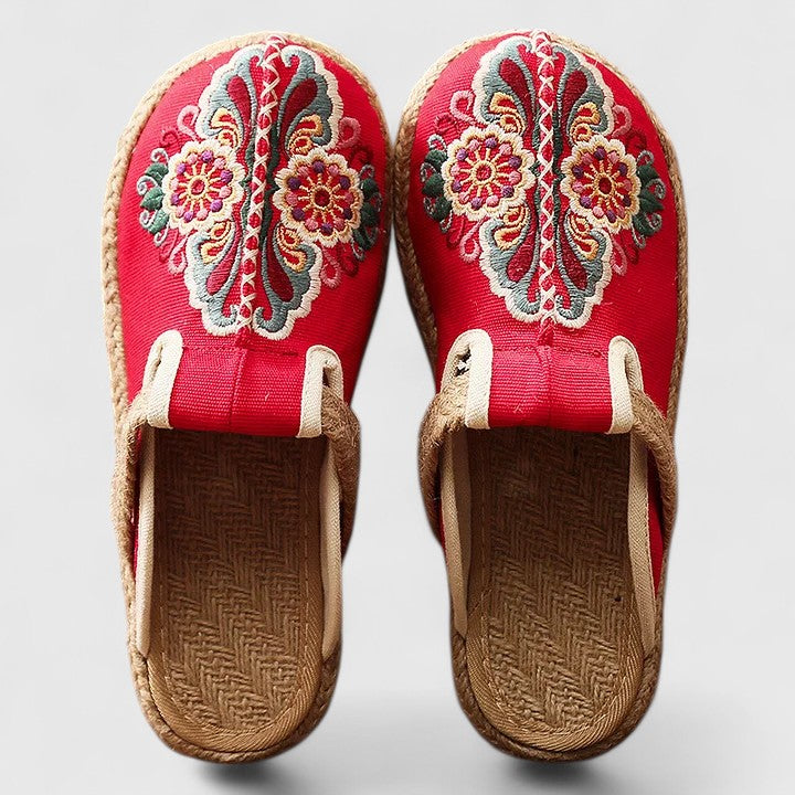 A woman wearing softly embroidered flat sandals, walking with ease on a sunny day.