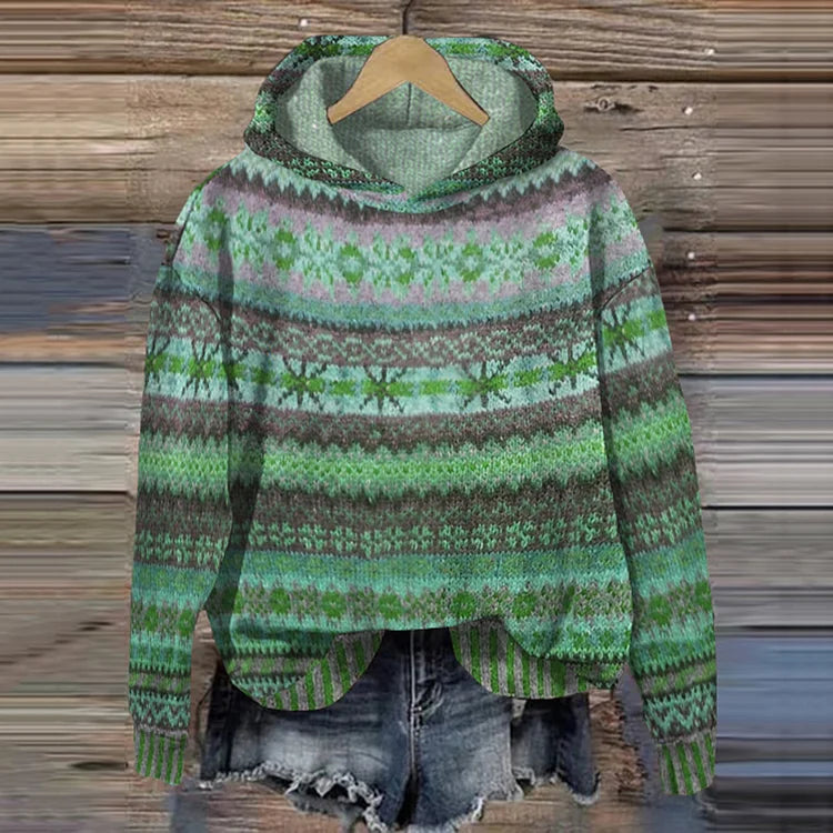 A woman wearing a retro hooded jumper in warm tones with a colourful Nordic pattern.