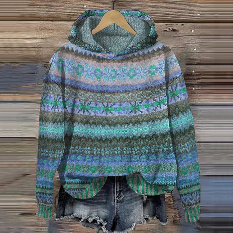 A woman wearing a retro hooded jumper in warm tones with a colourful Nordic pattern.