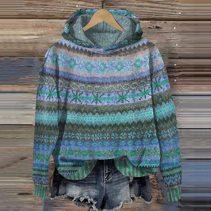 A woman wearing a retro hooded jumper in warm tones with a colourful Nordic pattern.