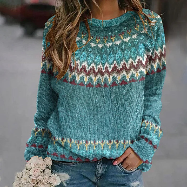 A woman wearing a teal jumper with a colourful retro zigzag pattern and a round neck, relaxed and cosy for autumn.