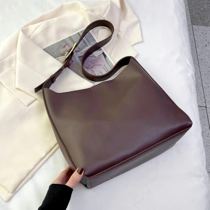A woman carrying a classic structured handbag over her shoulder