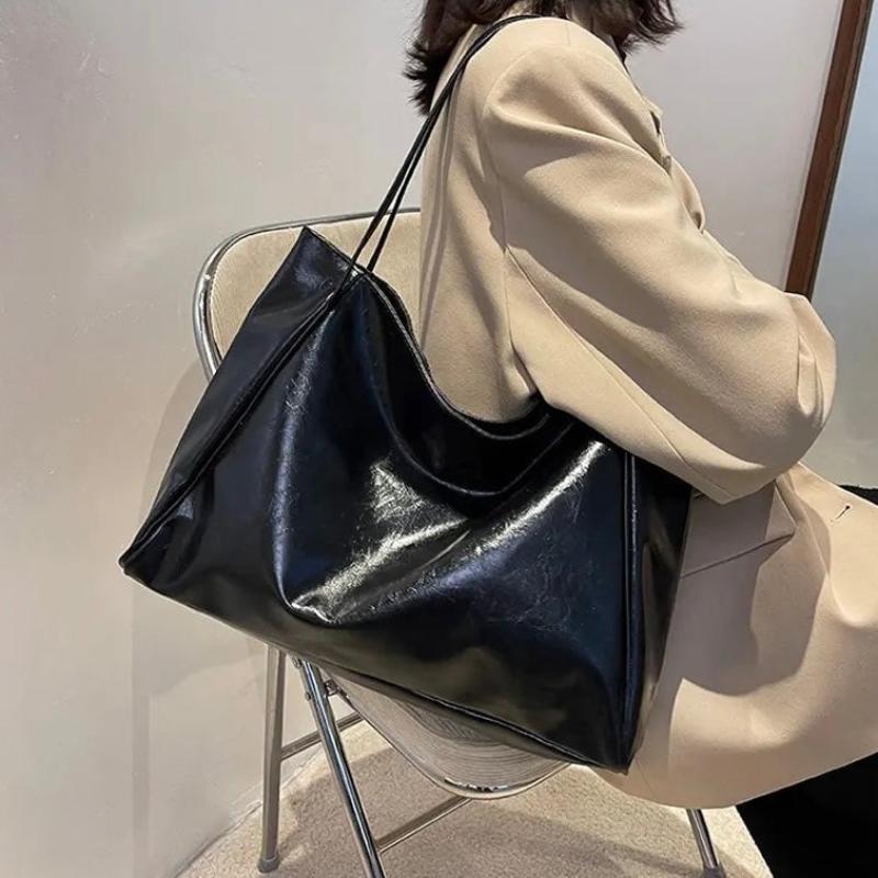 A woman holding a glossy taupe handbag on her arm at an evening occasion.