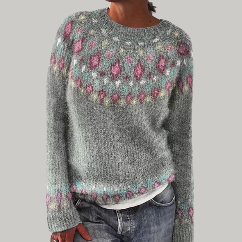 A woman wearing a grey round-neck jumper with a colourful Nordic patterned yoke.
