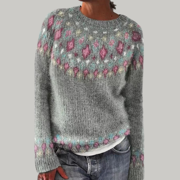 A woman wearing a grey round-neck jumper with a colourful Nordic patterned yoke.