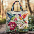 Quilted tote bag with a jewel-bright hummingbird hovering among white flowers on a structured padded body
