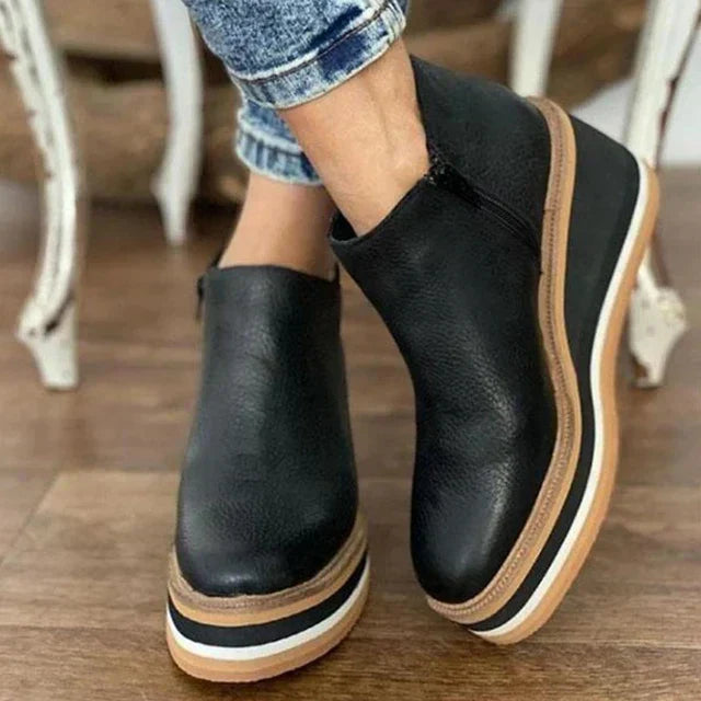 A woman wearing sleek minimalist ankle boots with jeans on a city break.