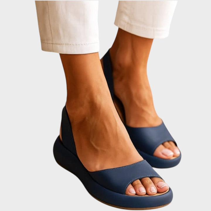 A woman walking gracefully in lightweight orthopaedic sandals with an adjustable strap on a sunny day.