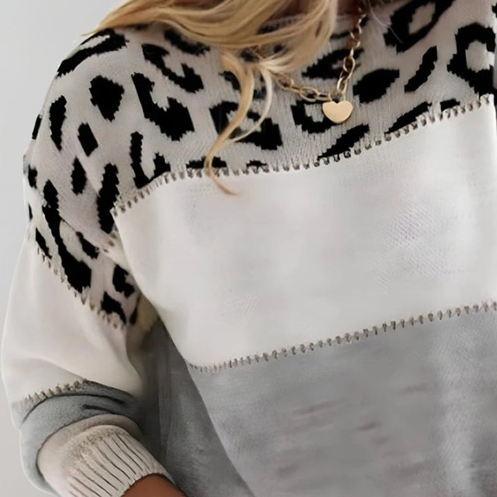 A woman wearing a grey leopard-print jumper, cosy and stylish, paired with jeans.