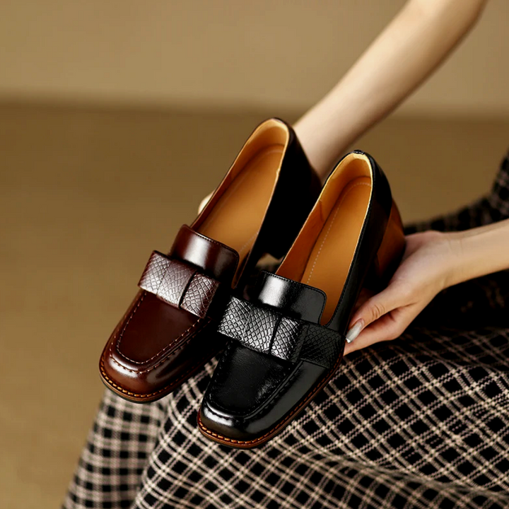 A woman wearing classic loafers with a subtle knot detail and tailored trousers