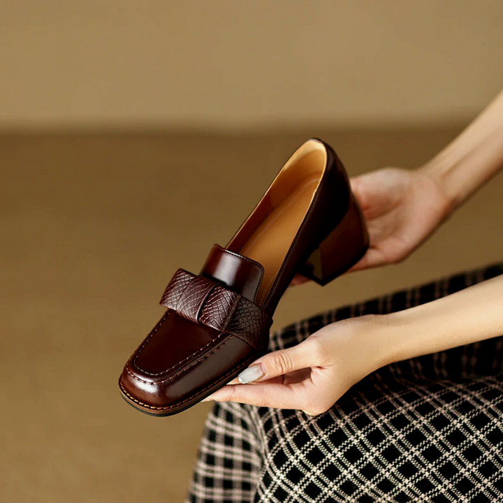 A woman wearing classic loafers with a subtle knot detail and tailored trousers
