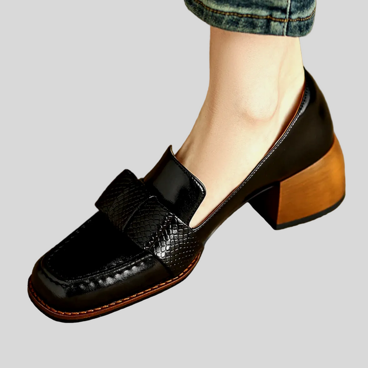A woman wearing classic loafers with a subtle knot detail and tailored trousers
