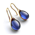 A pair of crystal drop earrings in blue and gold with faceted stones that catch the light