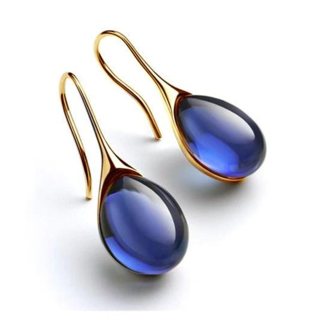 A pair of crystal drop earrings in blue and gold with faceted stones that catch the light