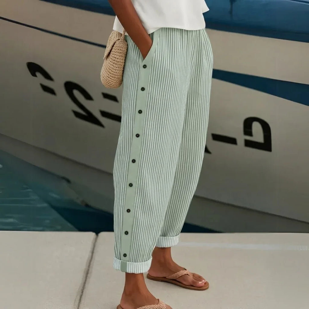 High-waisted striped trousers in black with decorative button detail along the waist