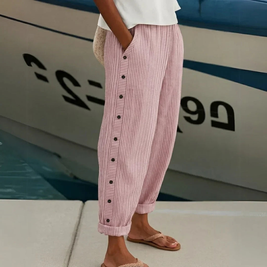High-waisted striped trousers in black with decorative button detail along the waist