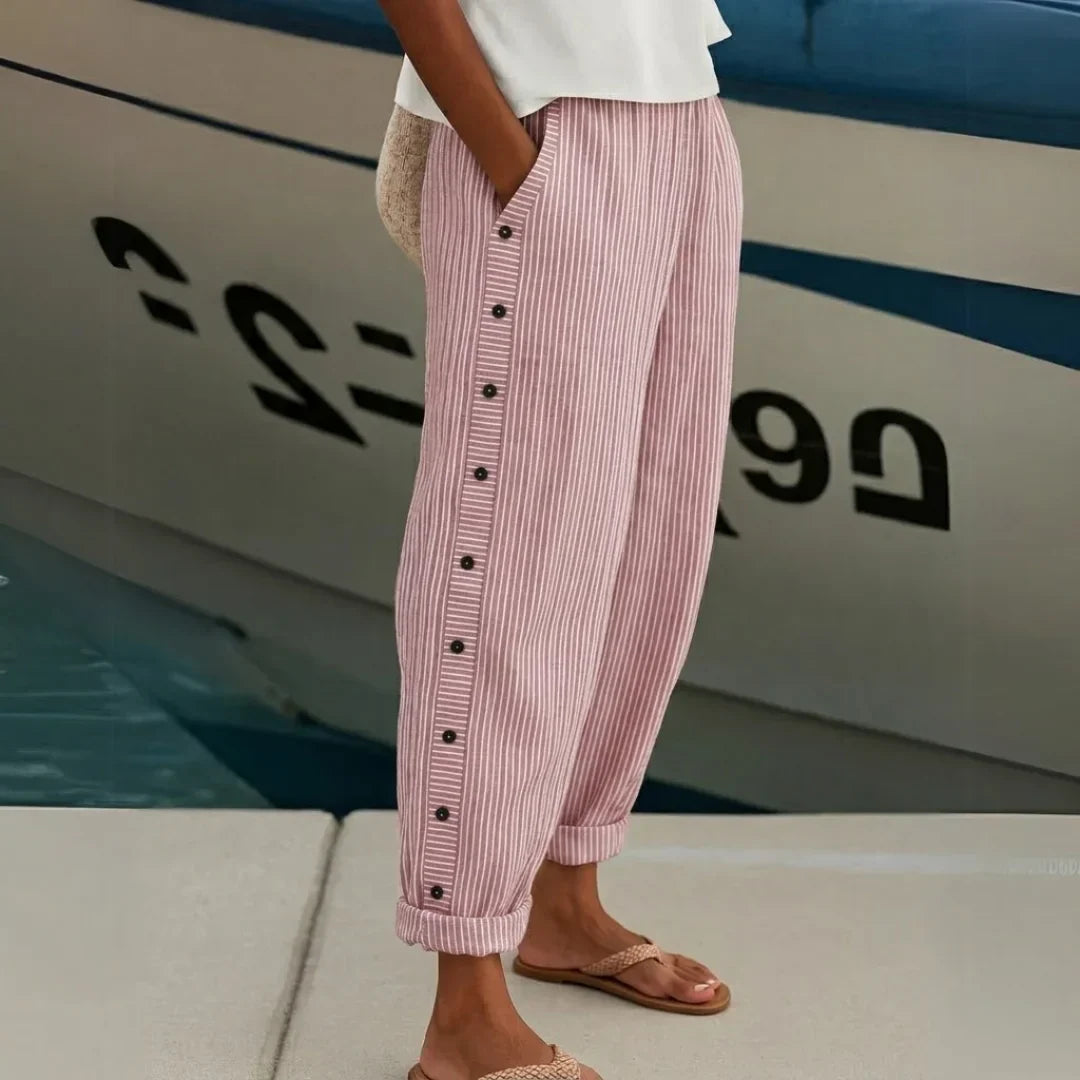 High-waisted striped trousers in black with decorative button detail along the waist