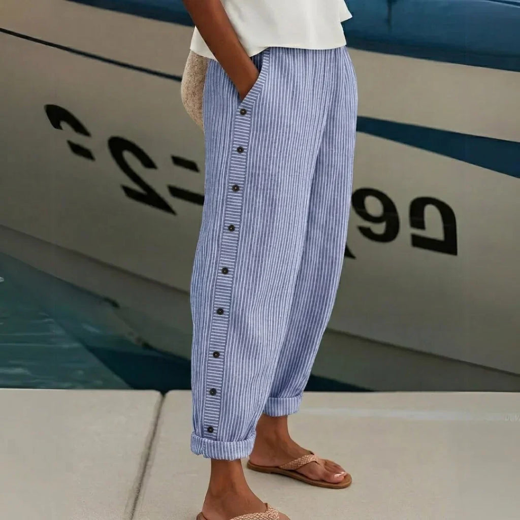 High-waisted striped trousers in black with decorative button detail along the waist
