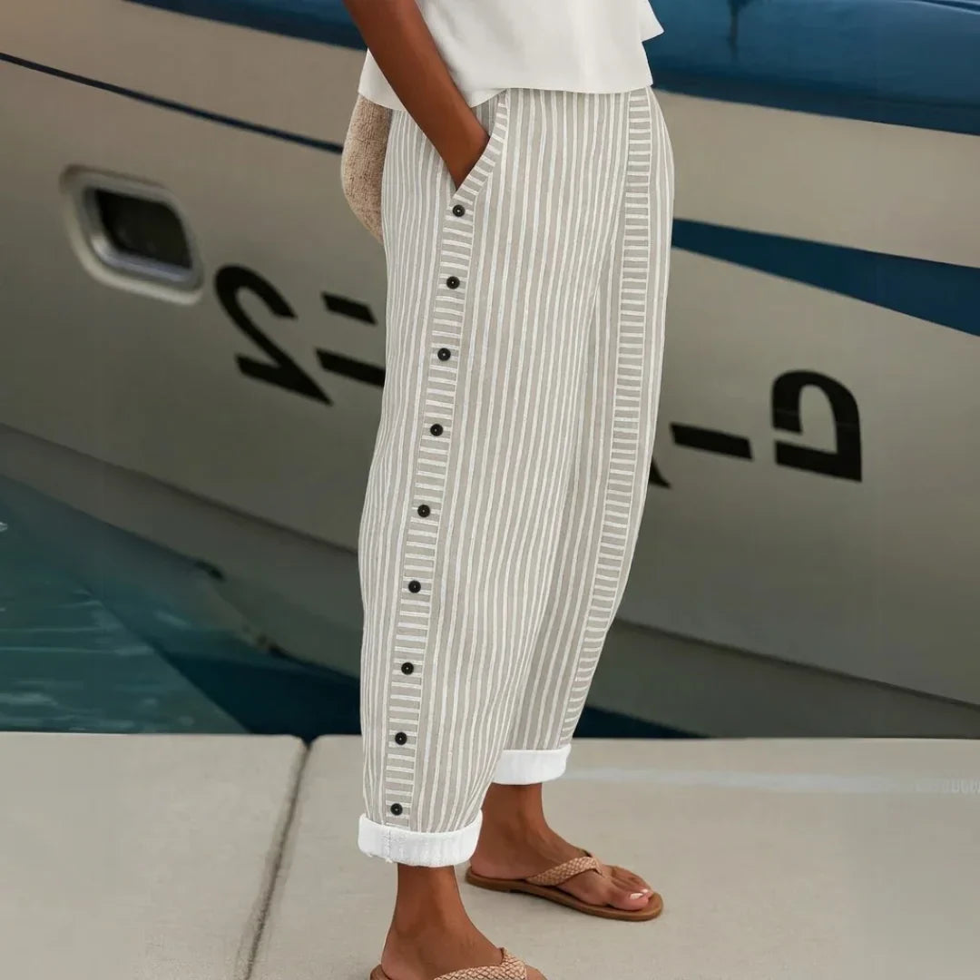 High-waisted striped trousers in black with decorative button detail along the waist