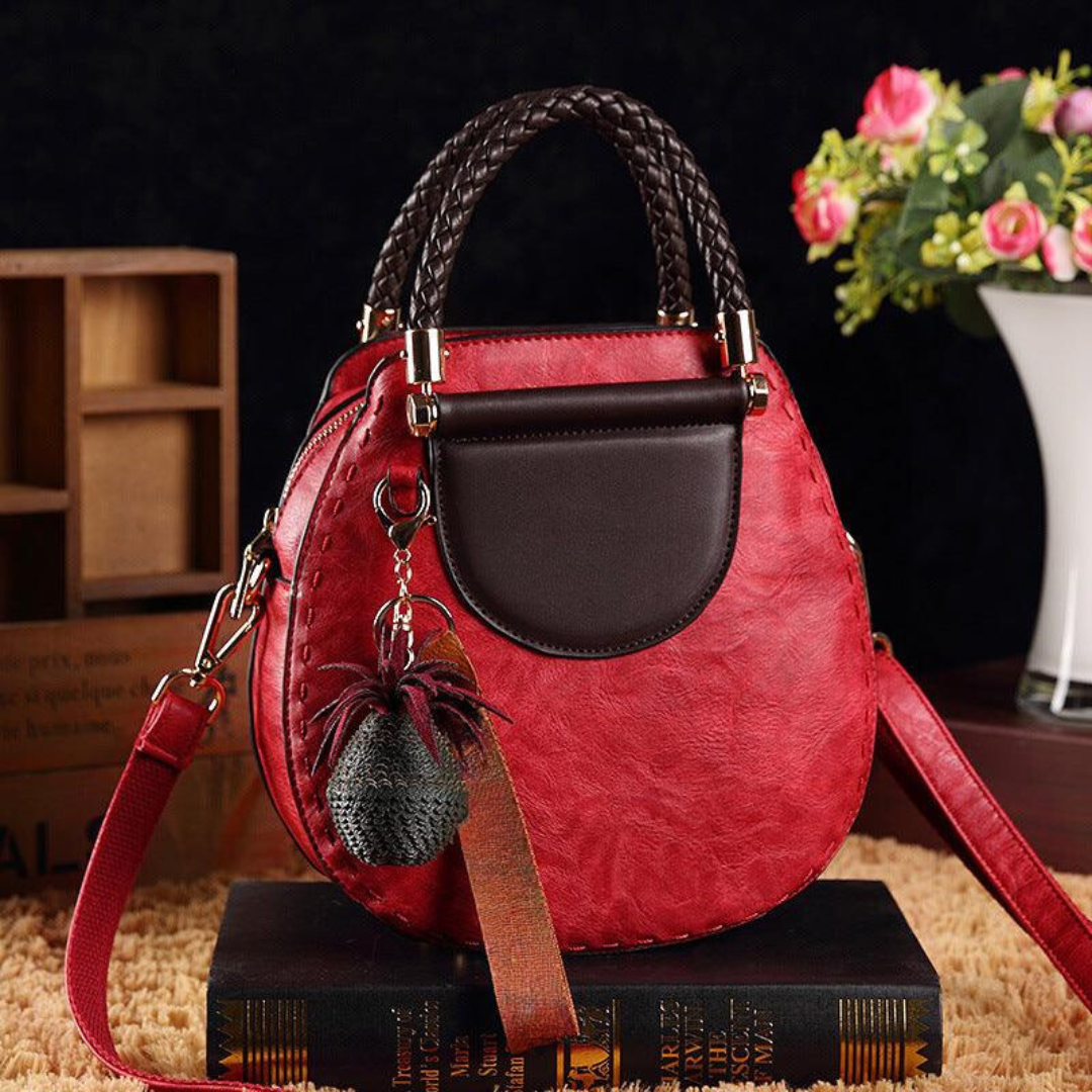 A woman carrying a small round top-handle handbag with a rich finish