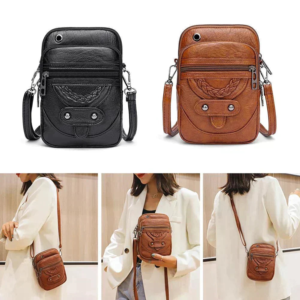 A woman holding a structured black top-handle handbag by the handle at a smart occasion.