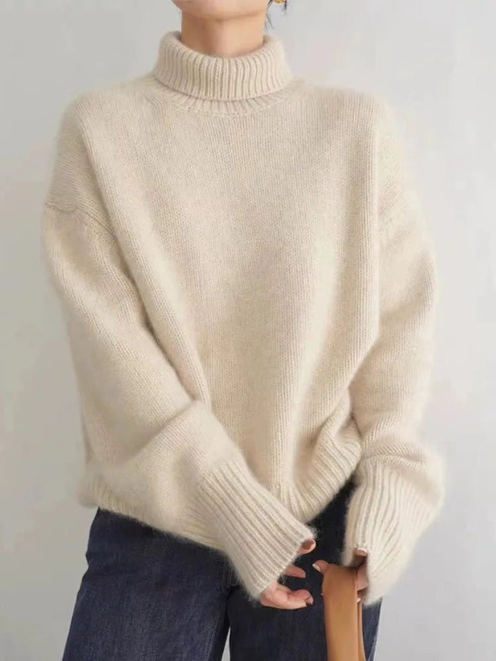 A woman wearing a beige roll-neck jumper, relaxed and warm, paired with trousers.