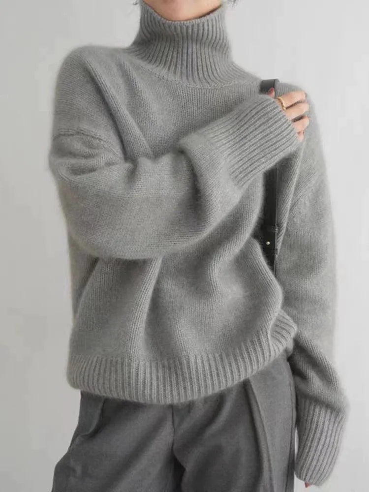 A woman wearing a beige roll-neck jumper, relaxed and warm, paired with trousers.