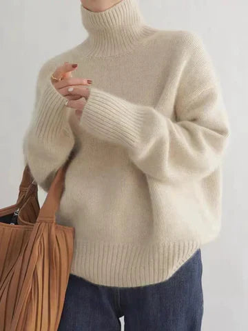 A woman wearing a beige roll-neck jumper, relaxed and warm, paired with trousers.