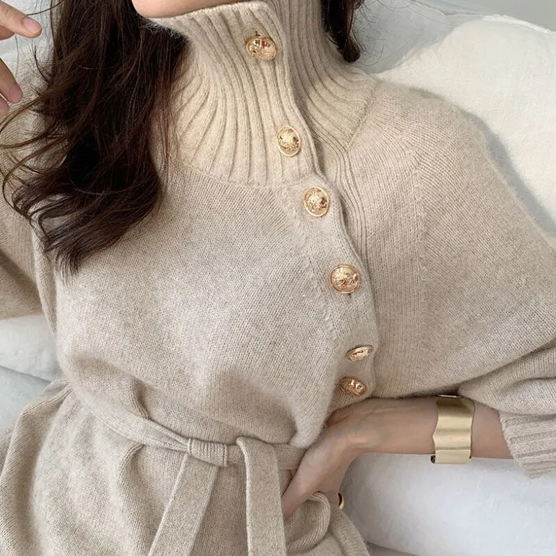 Woman in the Rosa cosy wrap dress with gold-tone buttons and a waist tie, holding a warm drink at home.