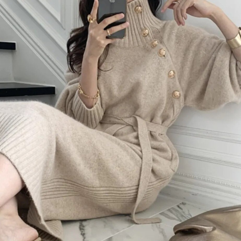 Woman in the Rosa cosy wrap dress with gold-tone buttons and a waist tie, holding a warm drink at home.