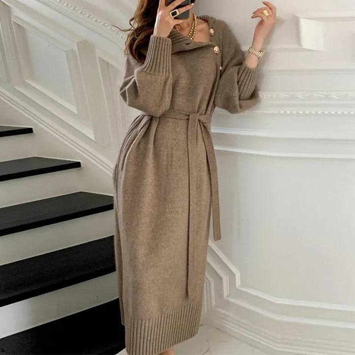 Woman in the Rosa cosy wrap dress with gold-tone buttons and a waist tie, holding a warm drink at home.