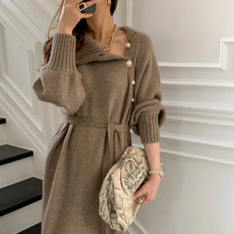 Woman in the Rosa cosy wrap dress with gold-tone buttons and a waist tie, holding a warm drink at home.