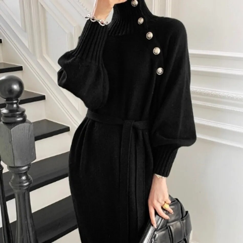 Woman in the Rosa cosy wrap dress with gold-tone buttons and a waist tie, holding a warm drink at home.