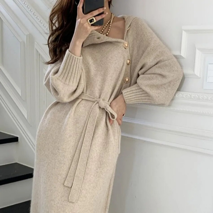 Woman in the Rosa cosy wrap dress with gold-tone buttons and a waist tie, holding a warm drink at home.