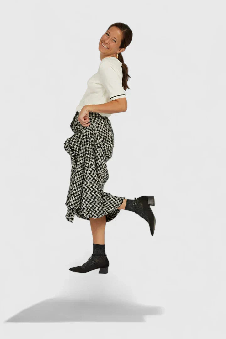A woman walking through the city in black pointed-toe block heels with slim ankle straps, relaxed and confident.