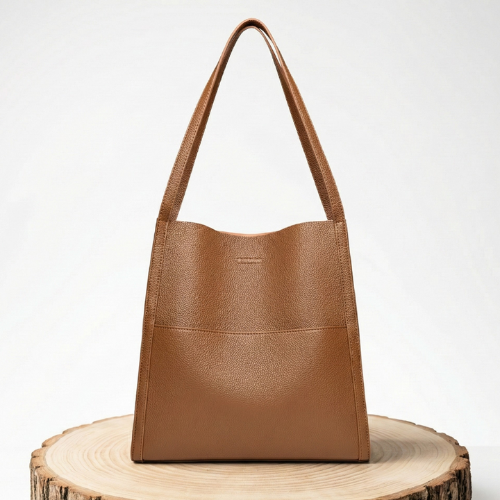 A woman carrying an elegant shoulder bag with clean lines over one shoulder in town