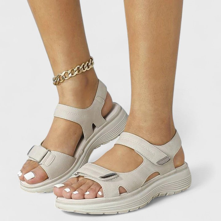 A woman walking gracefully in blue support sandals with a broad, cushioned footbed.