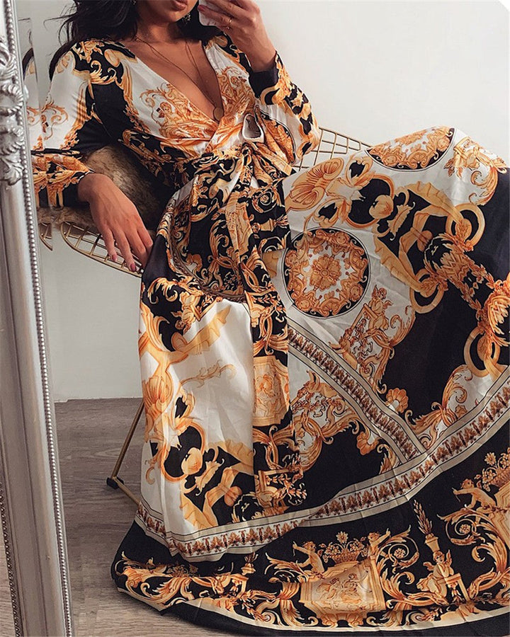 Woman at golden hour wearing the Tessa vintage print maxi dress with a waist belt and long statement sleeves.