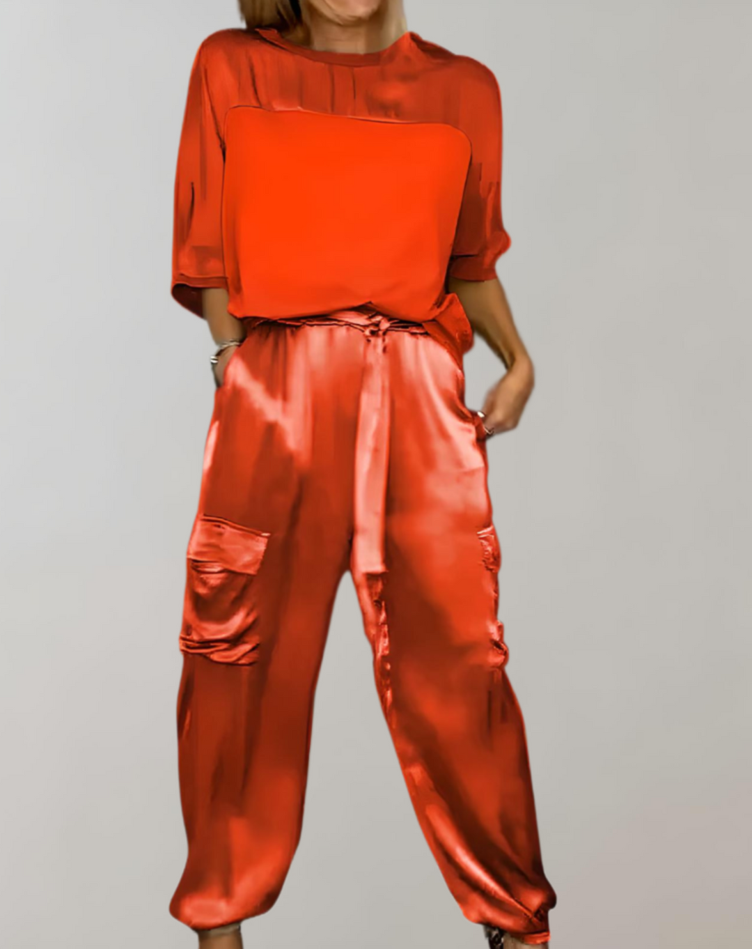 A woman wearing a silky-finish cargo top and trousers lounge set with pockets.