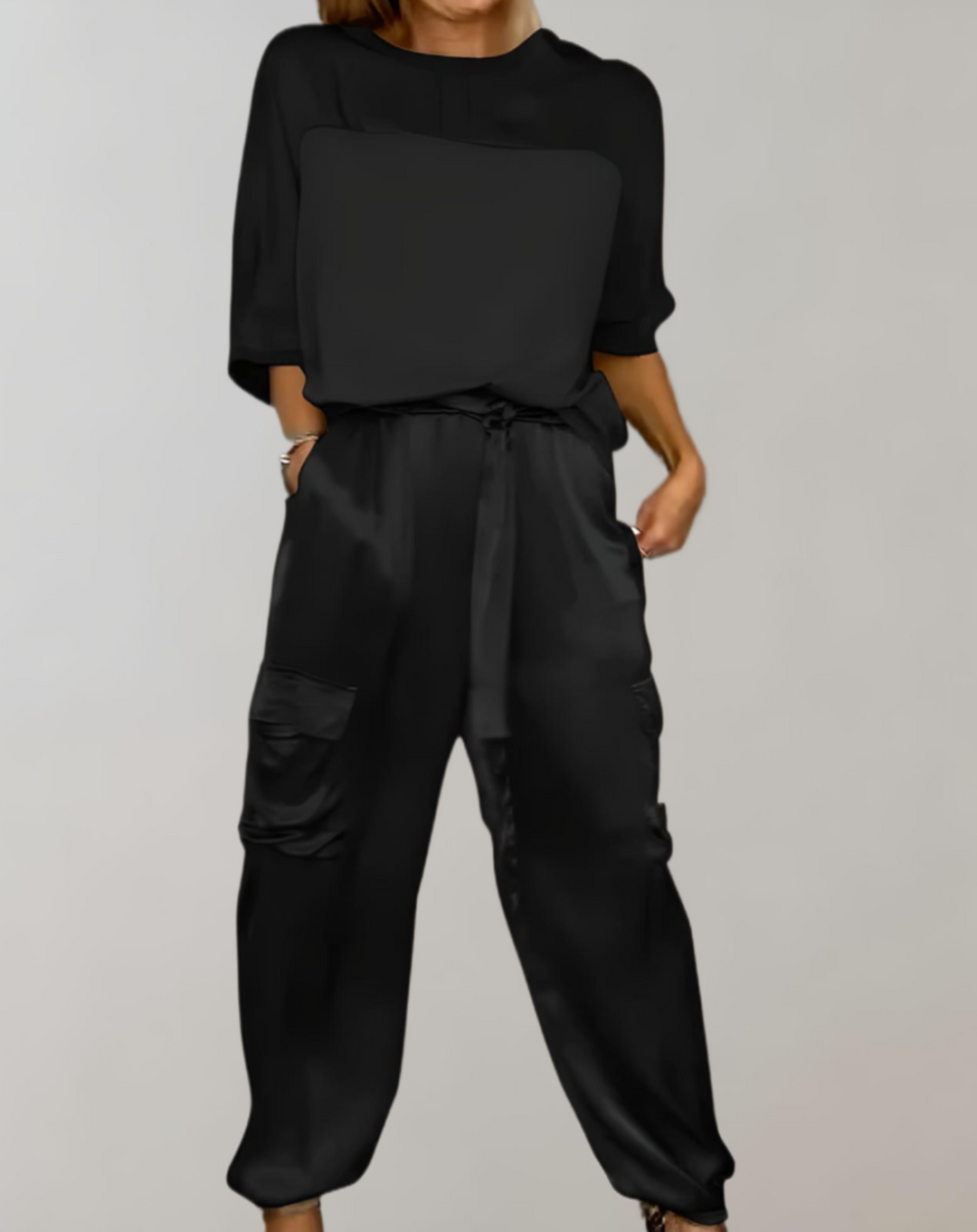 A woman wearing a silky-finish cargo top and trousers lounge set with pockets.