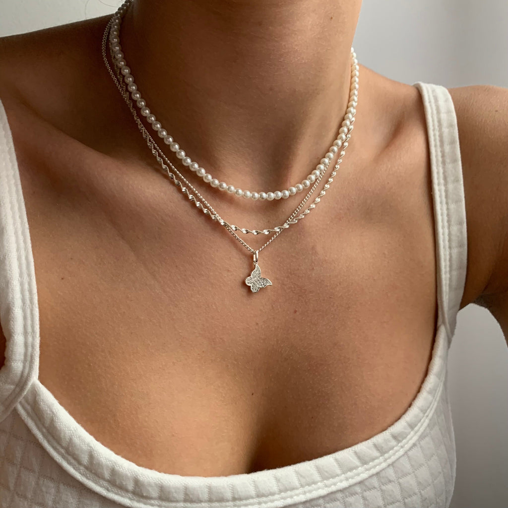 Double helix pendant necklace in gold tone on a plain white background