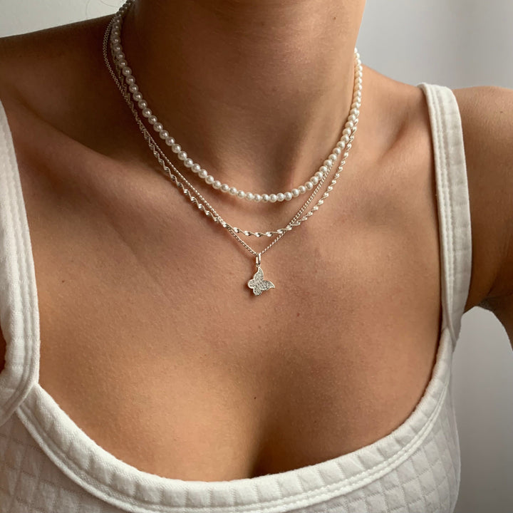 Double helix pendant necklace in gold tone on a plain white background