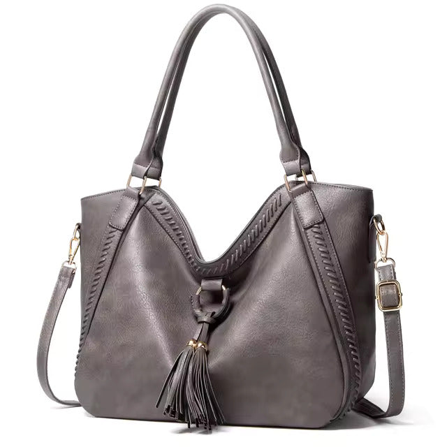 A woman carrying a soft pouch bag on her shoulder while out for a walk in town.