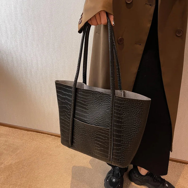 A woman carrying an elegant shoulder bag with a rich finish over one shoulder