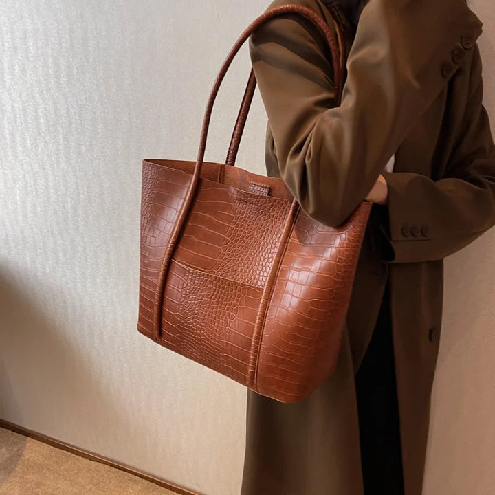 A woman carrying an elegant shoulder bag with a rich finish over one shoulder
