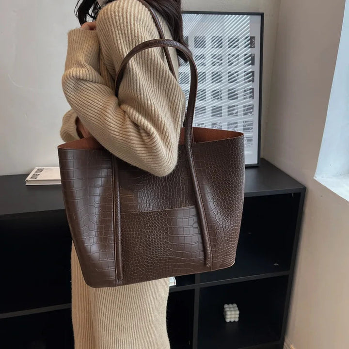 A woman carrying an elegant shoulder bag with a rich finish over one shoulder
