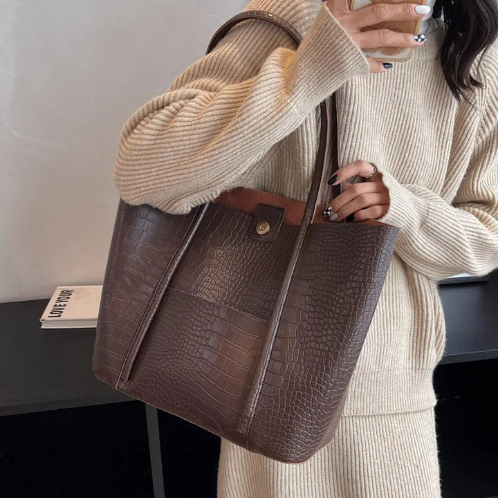A woman carrying an elegant shoulder bag with a rich finish over one shoulder